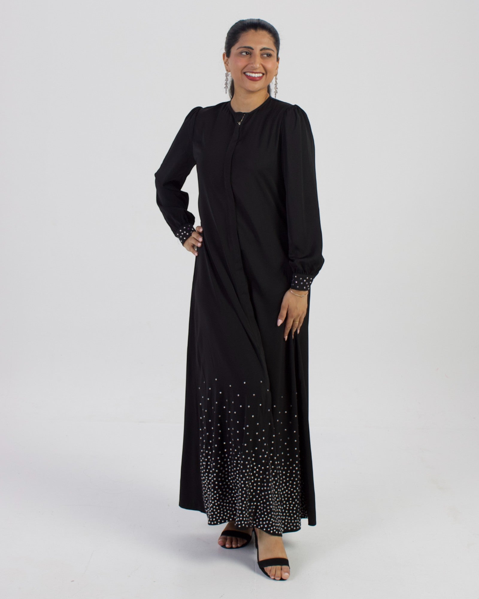 Model wearing Midnight Majesty studded long sleeve black abaya dress with silver stud embellishments on hem and cuffs.