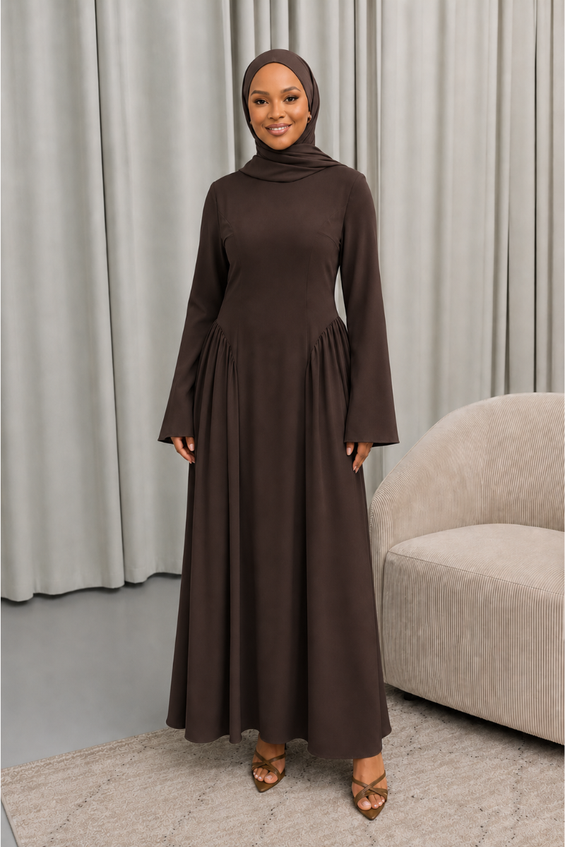 Veiled Muslim woman wearing a hijab in The Aura Dress, a full-length modest maxi dress with long sleeves, crew neckline, gathered pleated waist and flowing skirt