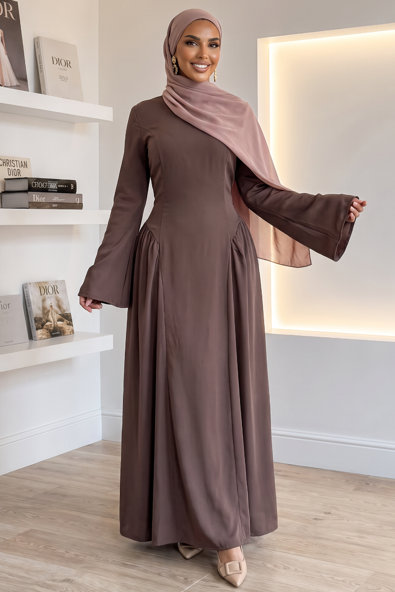 A woman wearing a long-sleeved, floor-length coffee maxi dress with a matching dusty rose hijab.