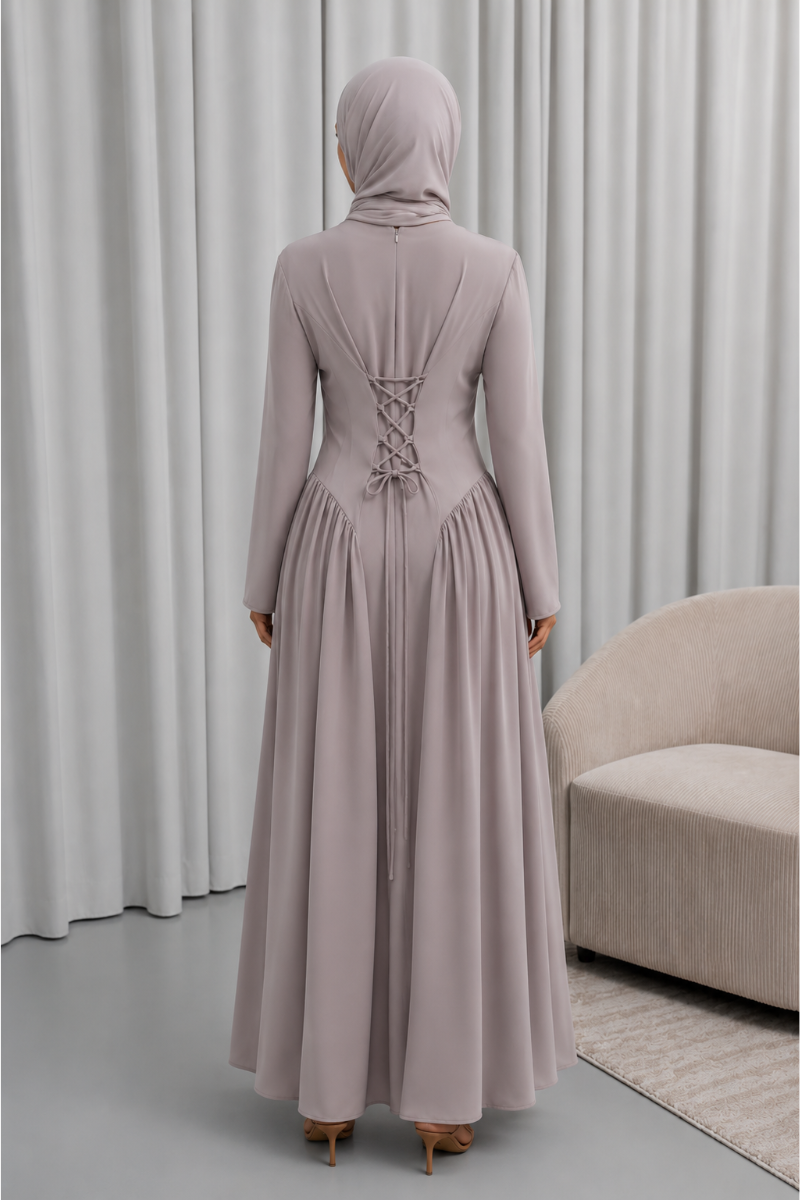 Veiled Muslim woman wearing a hijab in The Aura Dress, a full-length modest maxi dress with long sleeves, crew neckline, gathered pleated waist and flowing skirt