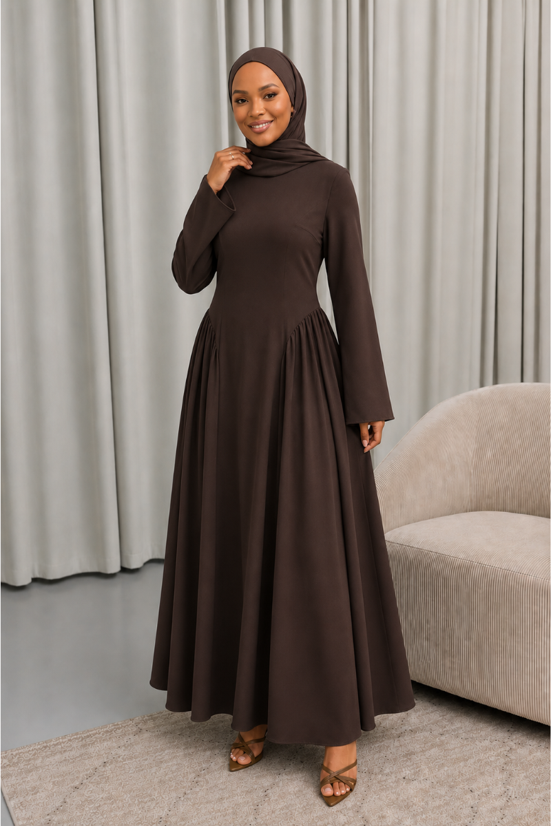 Veiled Muslim woman wearing a hijab in The Aura Dress, a full-length modest maxi dress with long sleeves, crew neckline, gathered pleated waist and flowing skirt