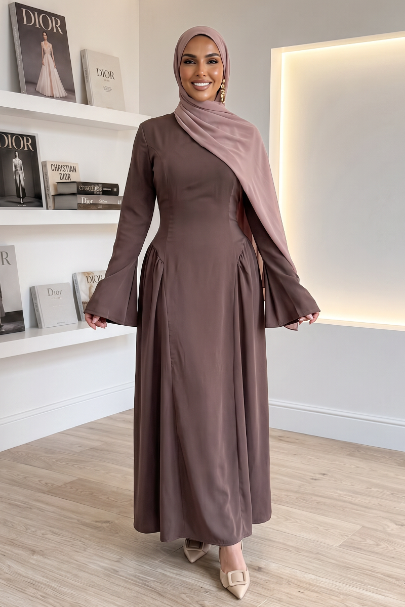 A woman modeling a long-sleeved coffee maxi abaya dress with flared bell sleeves and a matching hijab